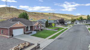 View of front of house featuring concrete driveway, a mountain view, a residential view, brick siding, and an attached garage