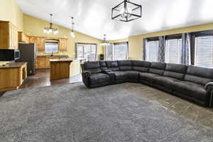 Living room featuring a chandelier, high vaulted ceiling, and dark colored carpet