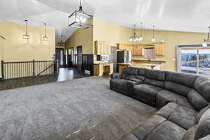 Living room featuring a chandelier, dark carpet, and high vaulted ceiling