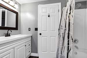 Bathroom featuring vanity, a textured wall, shower / bath combo with shower curtain, and wood finished floors