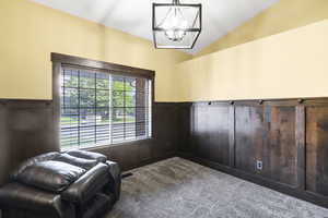Sitting room featuring a chandelier, carpet floors, lofted ceiling, and wainscoting