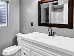 Bathroom featuring a textured wall, vanity, and wood finished floors