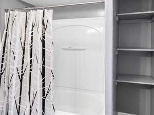 Full bath with wood finished floors, shower / tub combo with curtain, and a textured ceiling