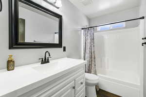 Full bath featuring vanity, shower / tub combo, and wood finished floors