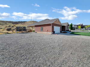 View of side of property with brick siding, driveway, an attached garage, a trampoline, and a shingled roof