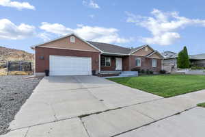 Single story home with a trampoline, brick siding, a garage, and a front yard