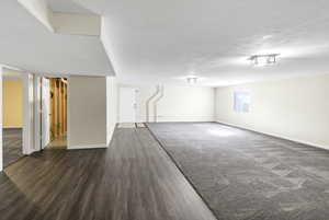 Below grade area with wood finished floors and a textured ceiling