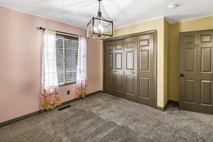 Unfurnished bedroom with dark carpet, a chandelier, and a closet