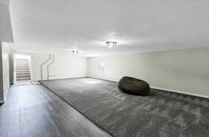 Below grade area featuring stairway, wood finished floors, and a textured ceiling