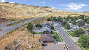 Aerial view of property and surrounding area featuring a mountain backdrop and nearby suburban area