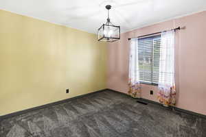 Spare room with a chandelier and dark colored carpet
