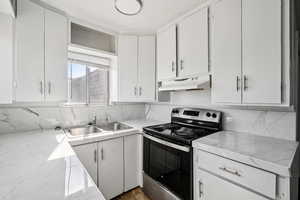 Kitchen featuring stainless steel electric stove, white cabinetry, backsplash, under cabinet range hood, and open shelves