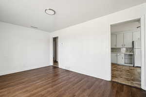Unfurnished room with dark wood-type flooring and baseboards