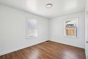 Empty room featuring baseboards and dark wood finished floors