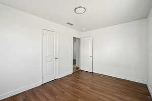 Unfurnished bedroom featuring baseboards and dark wood-style flooring