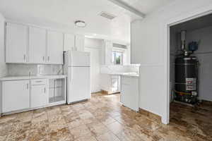Kitchen with a textured ceiling, white cabinetry, freestanding refrigerator, light countertops, and decorative backsplash
