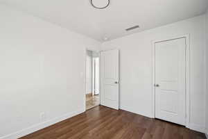 Unfurnished bedroom with baseboards and dark wood-style flooring