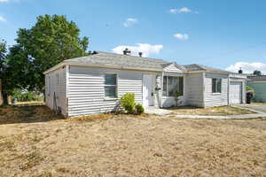 View of front of home with an attached garage, roof with shingles, a chimney, and driveway
