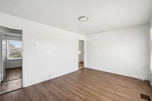 Spare room with dark wood-style flooring and baseboards