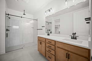Bathroom with a shower stall, double vanity, tile patterned floors, and a walk in closet