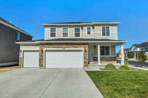 View of front of home with stucco siding, concrete driveway, a porch, a front yard, and stone siding