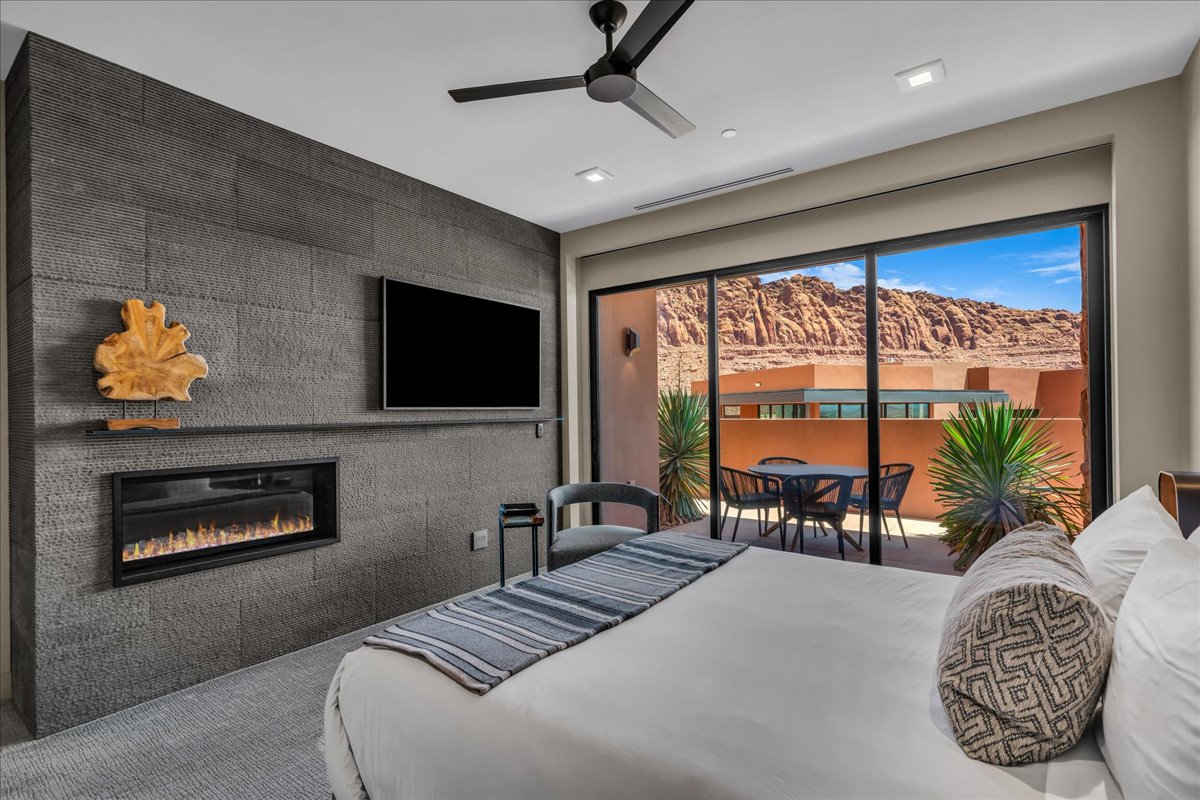 Carpeted bedroom featuring access to exterior, a glass covered fireplace, ceiling fan, and recessed lighting