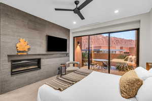Bedroom with a glass covered fireplace, access to exterior, recessed lighting, a ceiling fan, and an accent wall
