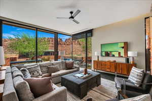 Tiled living area with a ceiling fan and a wall of windows