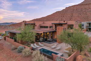 Back of house featuring a mountain view, stucco siding, an outdoor pool, and a patio area
