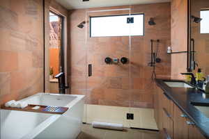 Full bath featuring a freestanding tub, a shower stall, double vanity, and tile walls