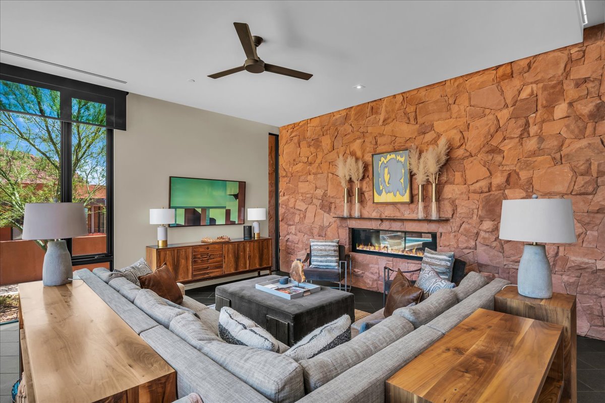 Living area featuring a ceiling fan and a glass covered fireplace