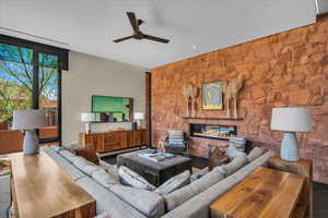 Living area featuring a ceiling fan and a glass covered fireplace