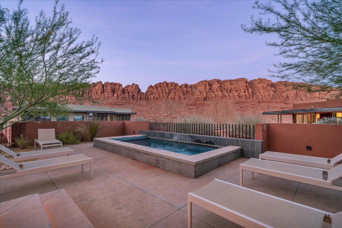 Pool at dusk with a patio area and a hot tub