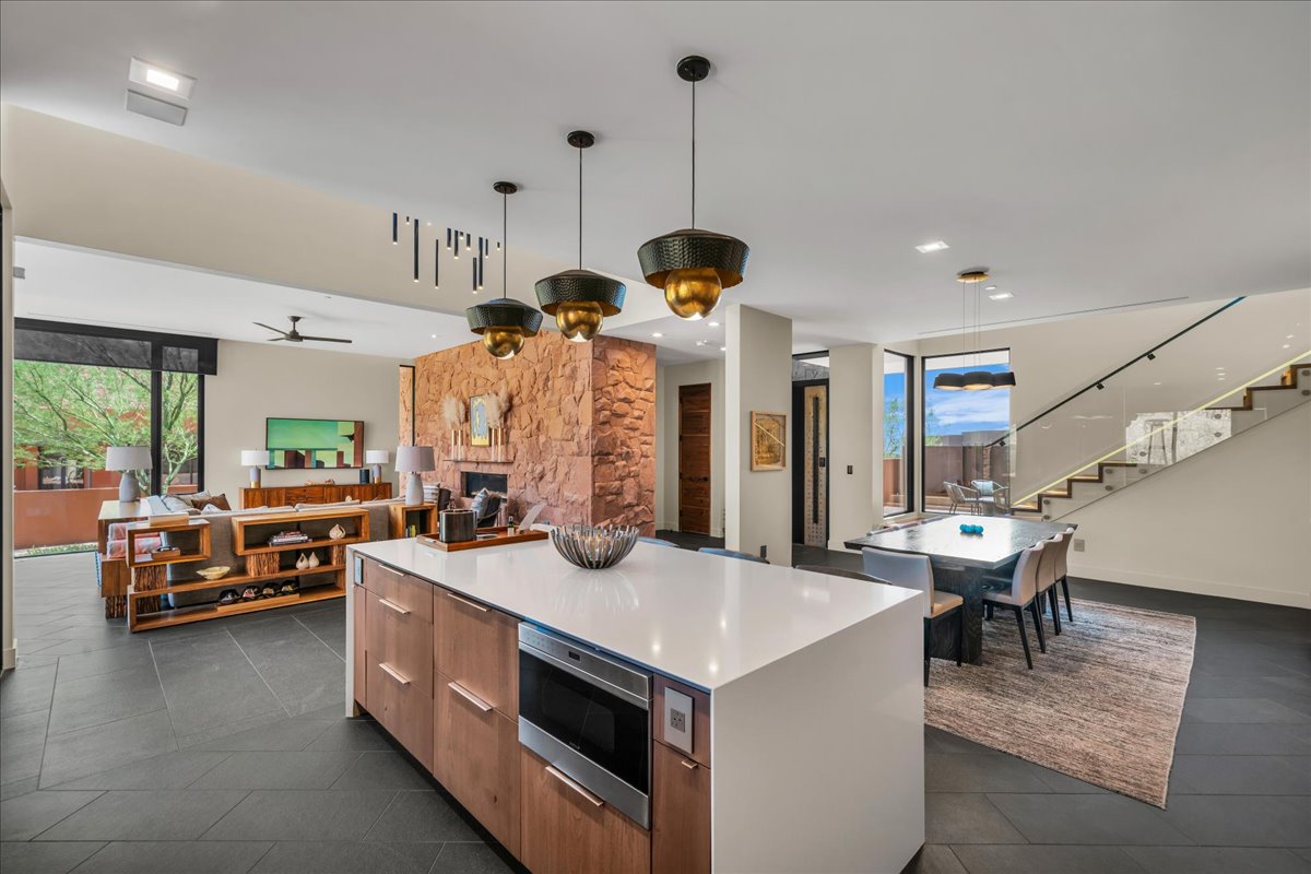 Kitchen with modern cabinets, open floor plan, a kitchen island, stainless steel microwave, and hanging light fixtures