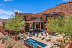 Back of property with a patio area, a mountain view, a hot tub, stucco siding, and a balcony