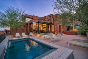 Back of house with a patio area, stucco siding, and stone siding
