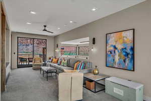 Carpeted living area featuring plenty of natural light, ceiling fan, and recessed lighting