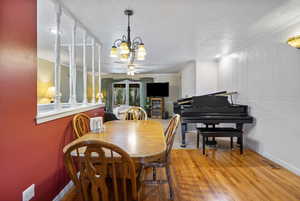 Dining area featuring light wood-style flooring, a chandelier, ornamental molding, a ceiling fan, and a textured ceiling