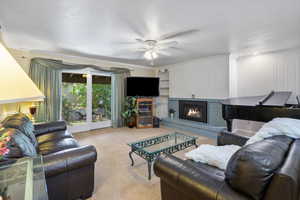 Living area with crown molding, carpet, ceiling fan, a brick fireplace, and a textured ceiling