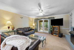 Living area with crown molding, carpet flooring, a ceiling fan, wallpapered walls, and a textured ceiling