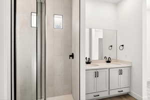 Full bathroom featuring double vanity and a stall shower