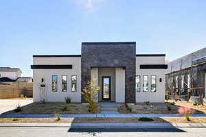 Modern home featuring stucco siding and stone siding
