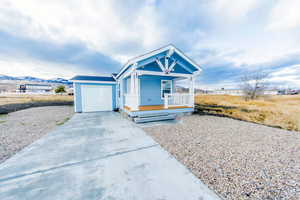 View of front of property with a porch, concrete driveway, and a garage