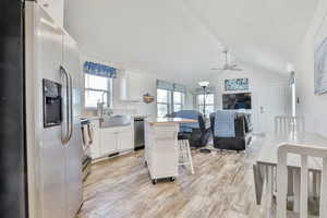 Kitchen with stainless steel appliances, ceiling fan, lofted ceiling, open floor plan, and plenty of natural light