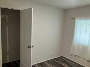 Unfurnished bedroom featuring dark wood finished floors and a closet