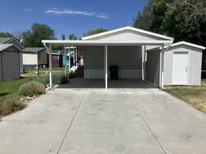 View of front facade featuring a shed, concrete driveway, and a carport