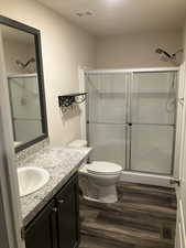 Bathroom featuring vanity, a stall shower, and wood finished floors