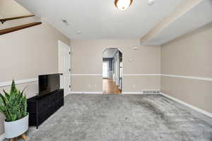 Unfurnished living room with arched walkways and carpet