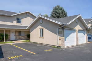 View of front of home featuring stucco siding, roof with shingles, and uncovered parking