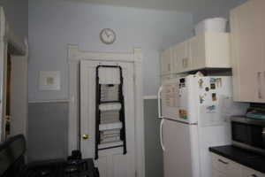745-Kitchen featuring stainless steel microwave, freestanding refrigerator, white cabinets, range, and dark countertops